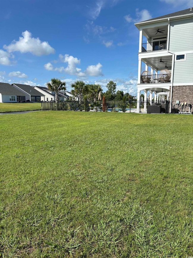 View of yard featuring a ceiling fan and a balcony