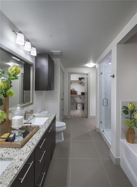 Full bathroom with dual bowl vanity, tile flooring, toilet, and independent shower and bath