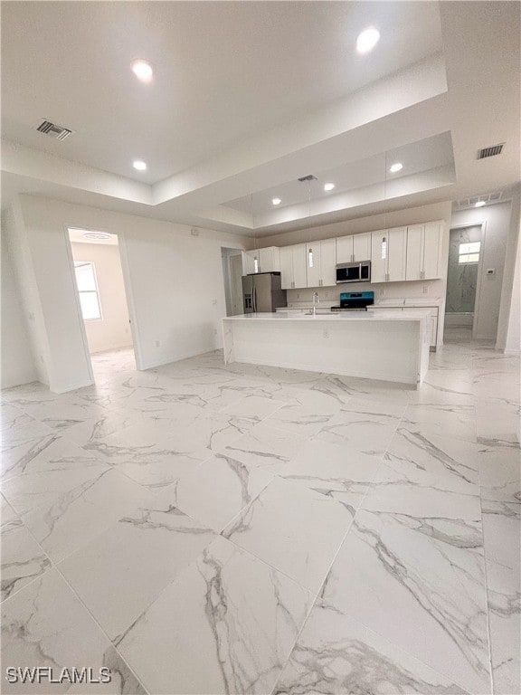 Unfurnished living room featuring a tray ceiling,