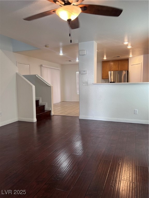 Unfurnished living room featuring ceiling fan, sta