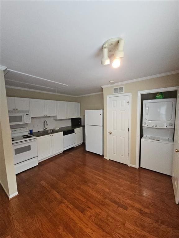 Kitchen featuring white cabinets, white appliances, dark wood-style flooring, stacked washer / drying machine, and dark countertops
