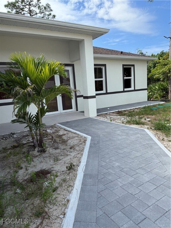 Doorway to property with stucco siding and a shingled roof
