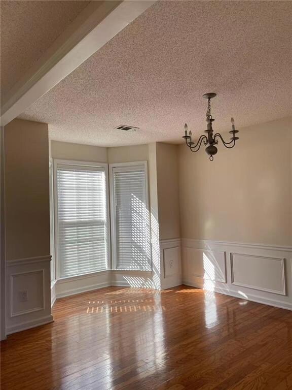 Spare room with an inviting chandelier, hardwood /
