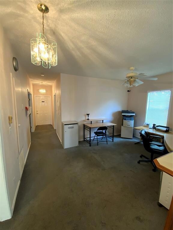 Office with dark colored carpet, a textured ceilin