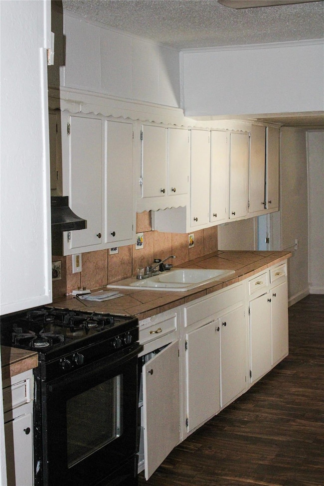 Kitchen with a textured ceiling, dark wood-type fl