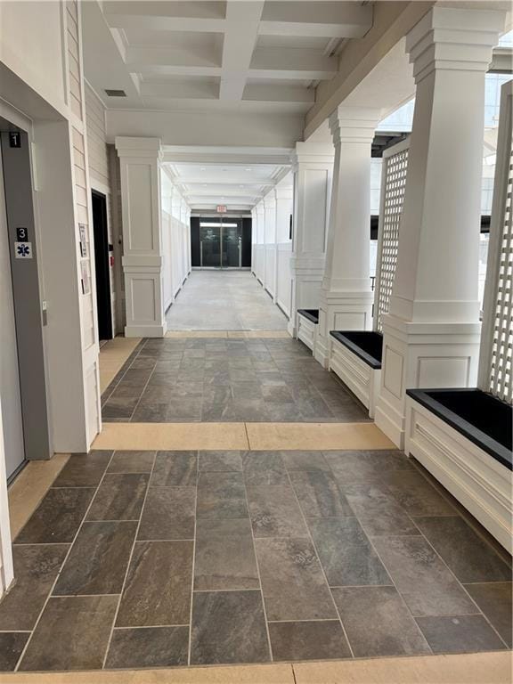 Hallway featuring beamed ceiling, coffered ceiling, a decorative wall, and elevator