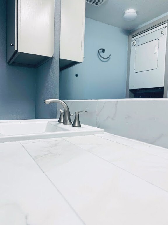 Bathroom with visible vents, a sink, and washer /