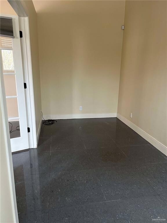 Empty room featuring granite finish floor and baseboards