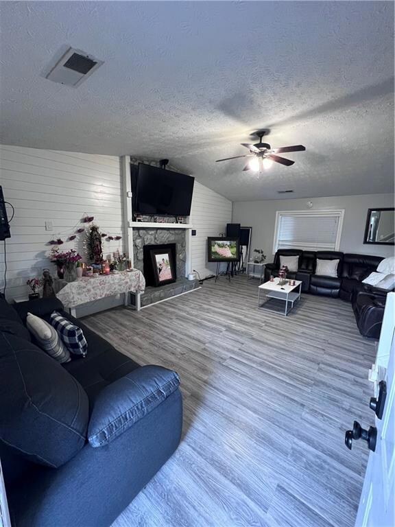 Living room featuring ceiling fan, a stone firepla