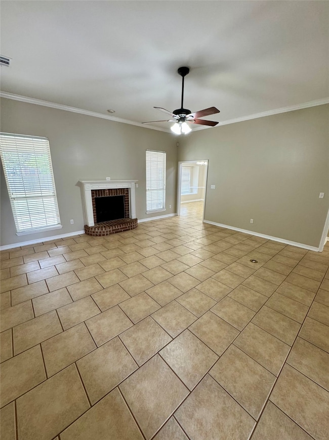 Unfurnished living room with a brick fireplace, crown molding, light tile patterned floors, and ceiling fan