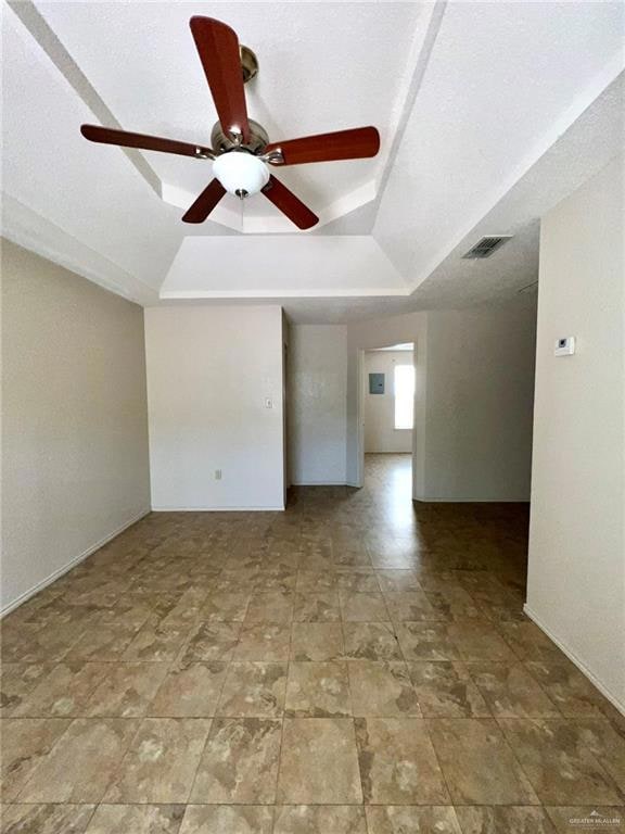 Living room featuring visible vents, baseboards, a raised ceiling, and a ceiling fan