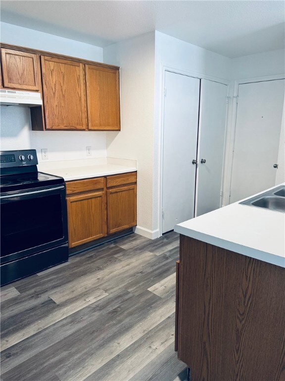 Kitchen with black electric range, brown cabinets,