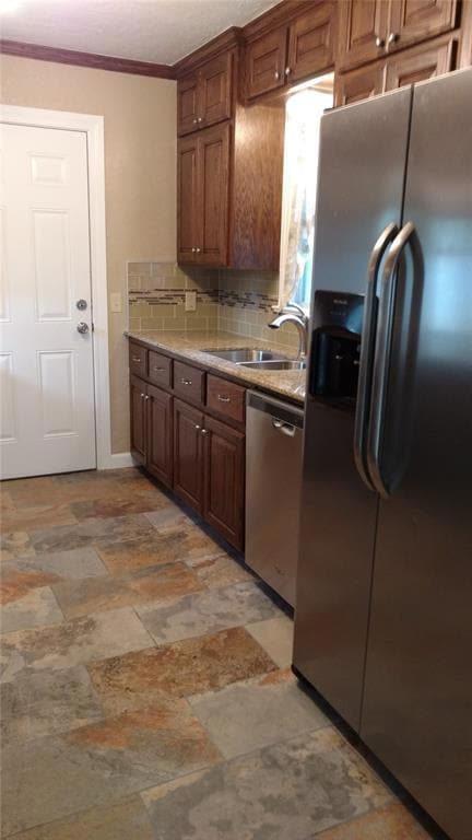 Kitchen featuring stainless steel appliances, backsplash, light stone counters, and ornamental molding