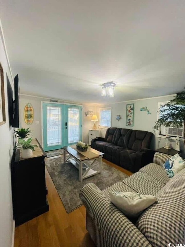 Living area with wood finished floors, healthy amount of natural light, and french doors