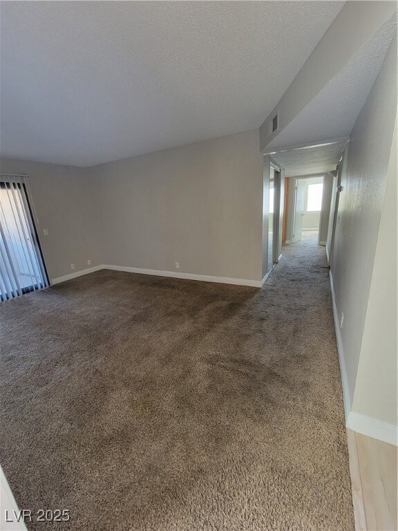 Carpeted spare room featuring baseboards and a tex