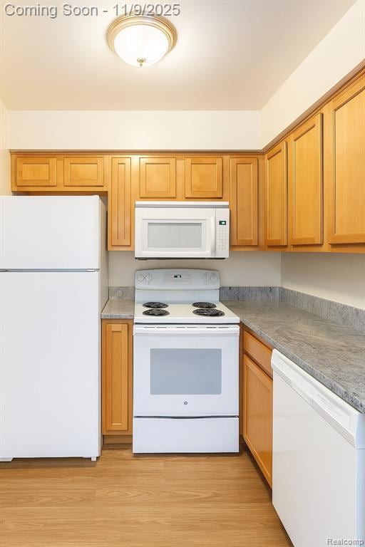 Kitchen featuring white appliances, light wood-style flooring, and light countertops