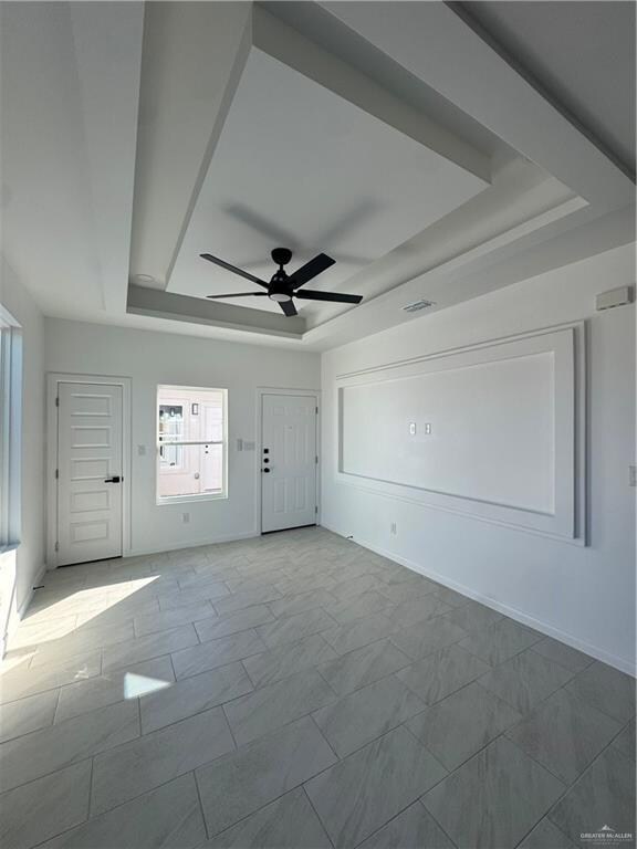Empty room with a raised ceiling and a ceiling fan
