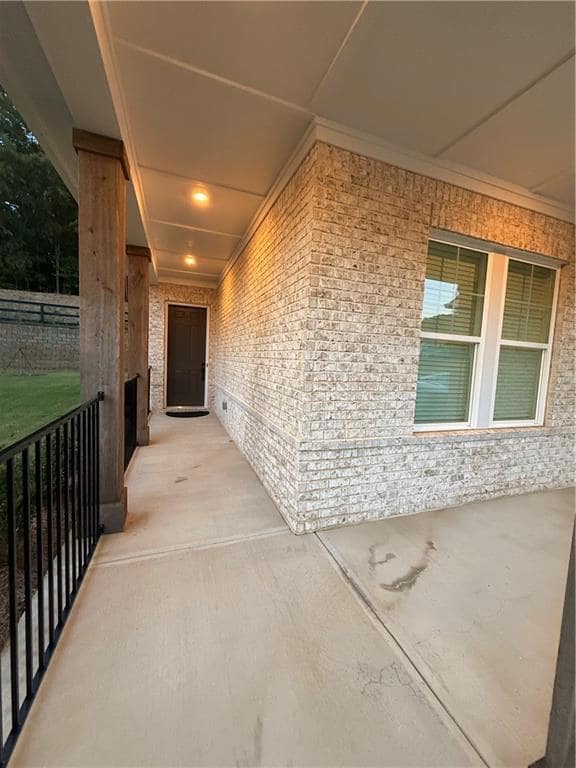 View of exterior entry with a patio area and brick siding