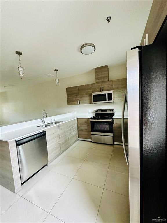 Kitchen with stainless steel appliances, modern cabinets, light tile patterned flooring, hanging light fixtures, and a peninsula