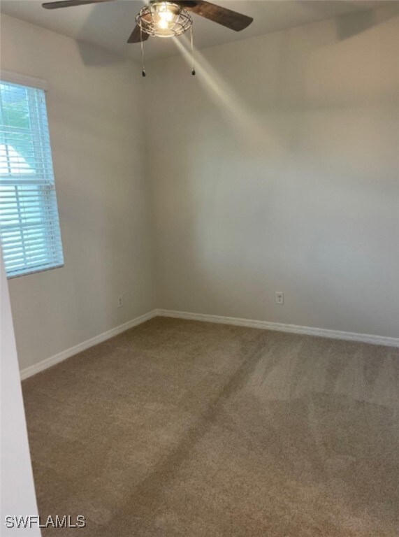 Carpeted spare room featuring ceiling fan