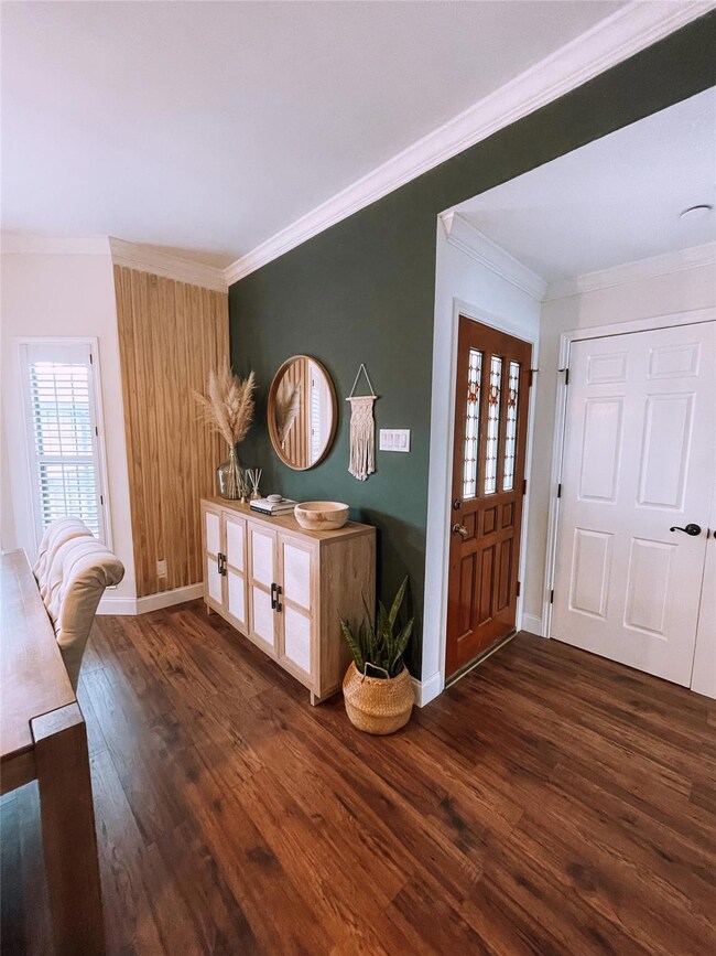 Entryway featuring ornamental molding and dark har