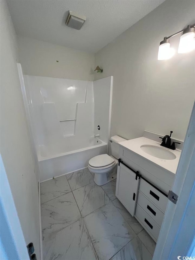 Bathroom featuring vanity, shower / washtub combination, a textured ceiling, and light marble finish flooring