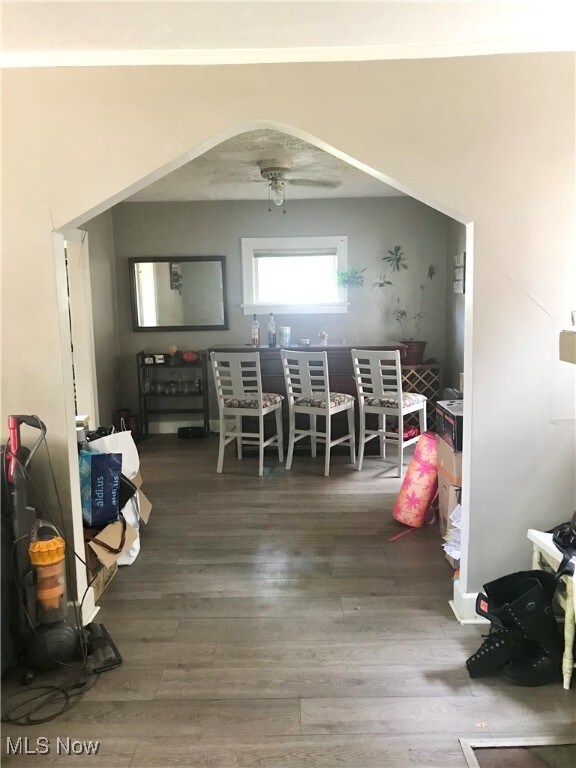Dining area with arched walkways, wood finished floors, and a ceiling fan