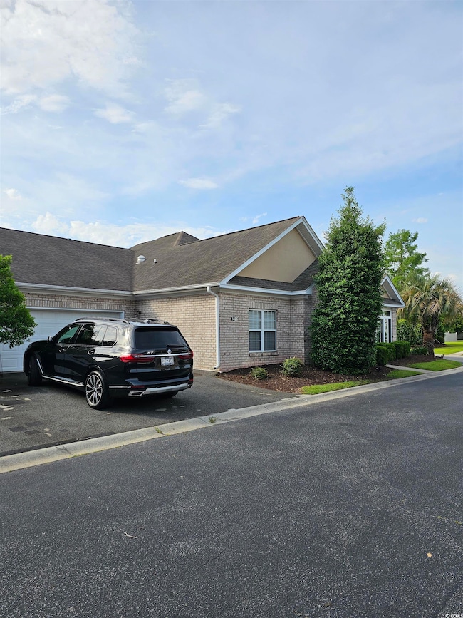 View of front of home with asphalt driveway, an attached garage, and brick siding