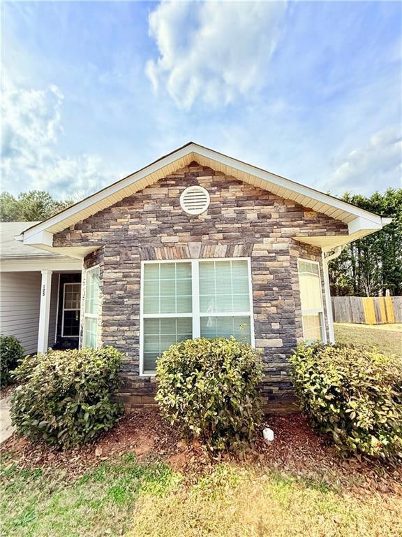 View of home's exterior with stone siding and fenc