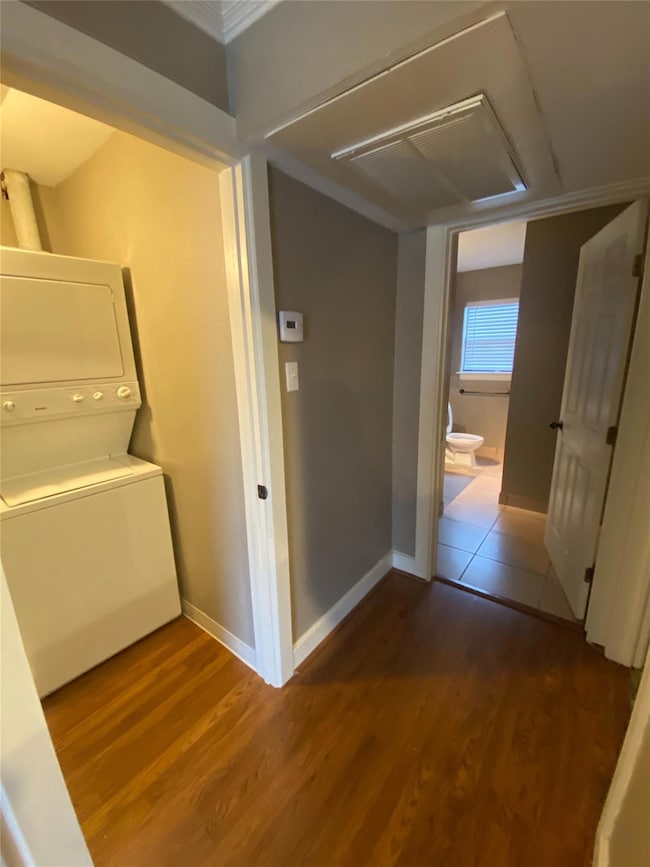 Hallway featuring stacked washer and dryer, wood f