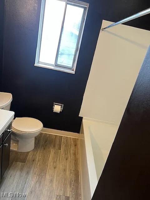 Full bath with light wood-style flooring and vanity