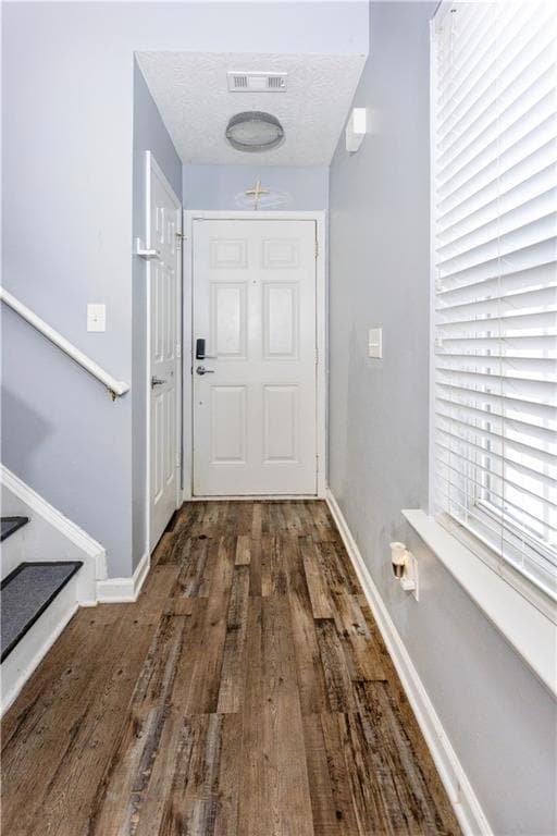 Entryway featuring wood finished floors, stairway, and a textured ceiling