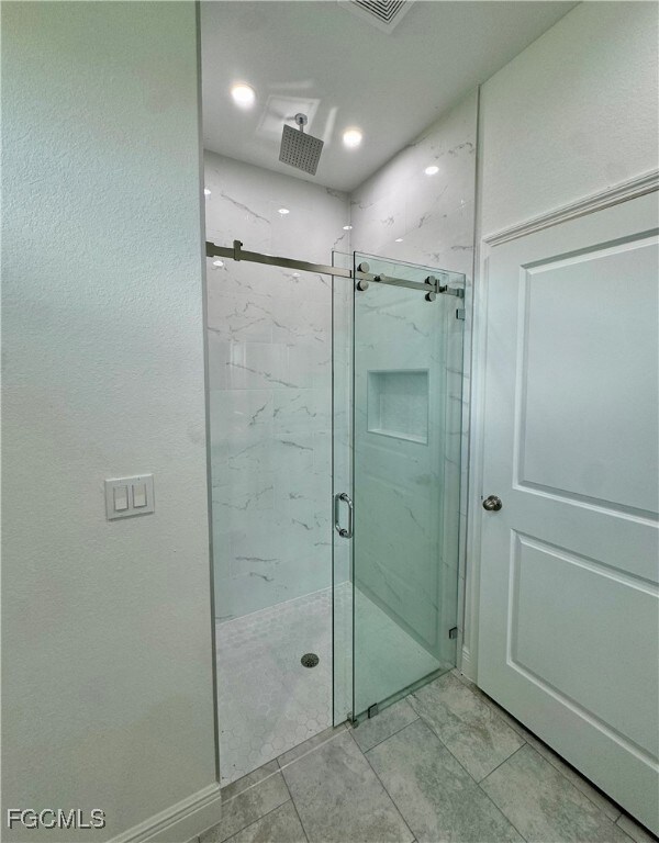 Full bath featuring a marble finish shower and a textured wall