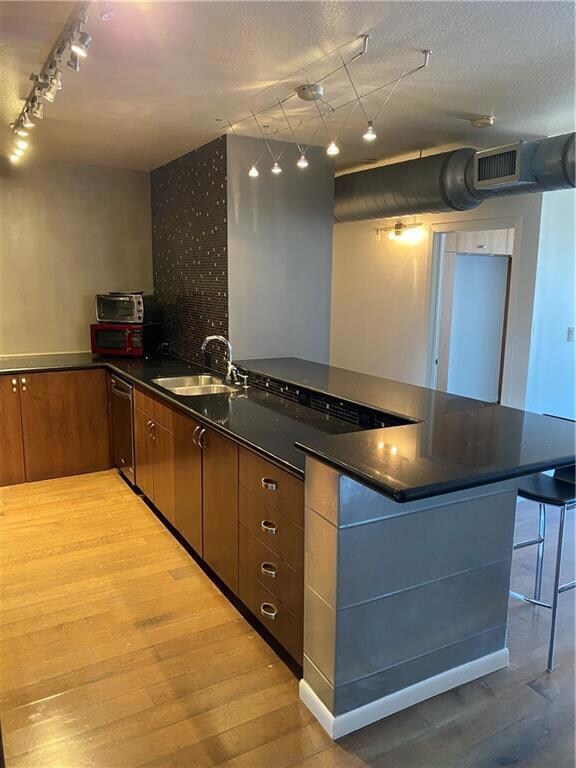 Kitchen with track lighting, a peninsula, dark st