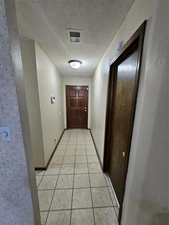Hall featuring a textured ceiling, visible vents, 