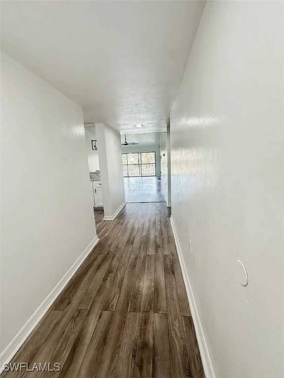 Hall featuring dark wood finished floors and baseb