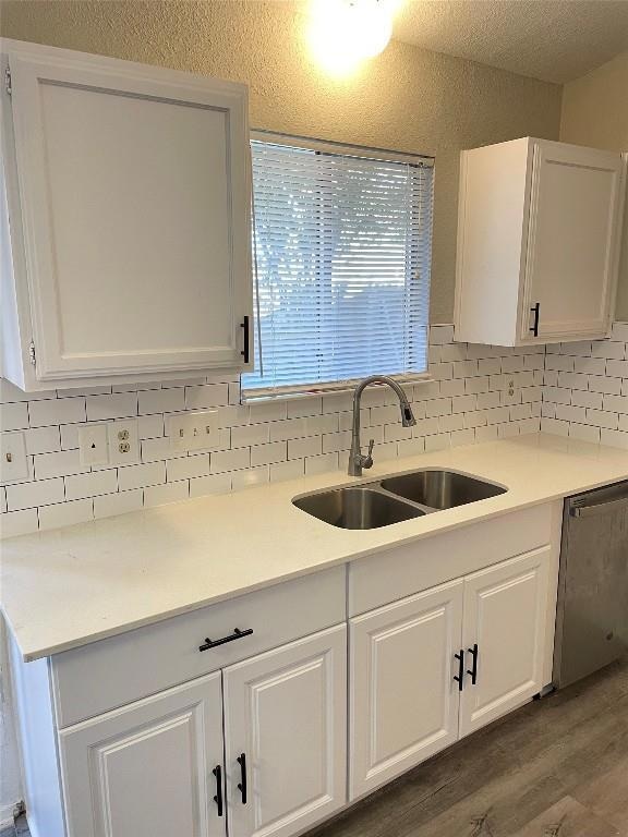 Kitchen featuring a sink, white cabinets, dark wo