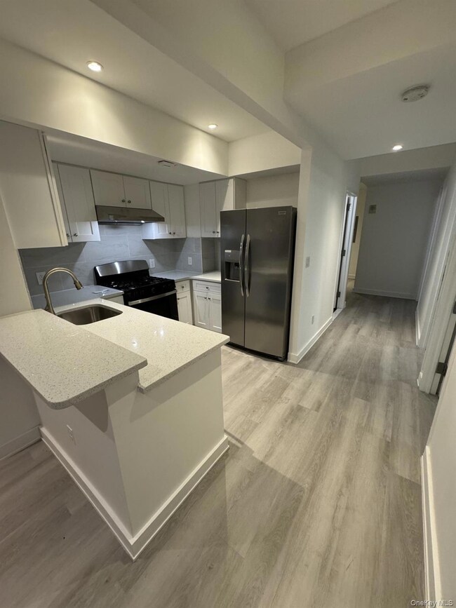 Kitchen with tasteful backsplash, light stone countertops, fridge with ice dispenser, range with gas stovetop, and recessed lighting