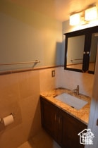 Bathroom featuring tile walls, wainscoting, vanity, and tile patterned floors