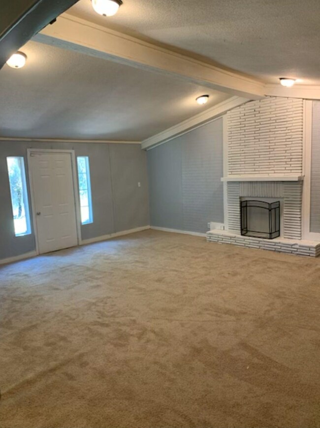 Unfurnished living room with a brick fireplace, or