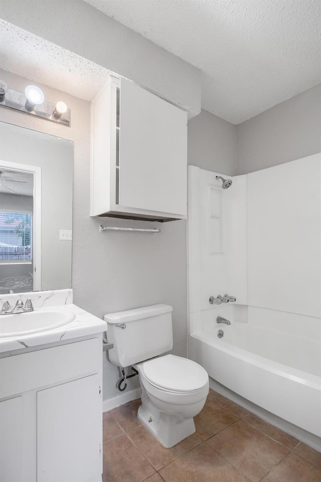 Full bathroom featuring  shower combination, light tile patterned floors, a textured ceiling, and vanity