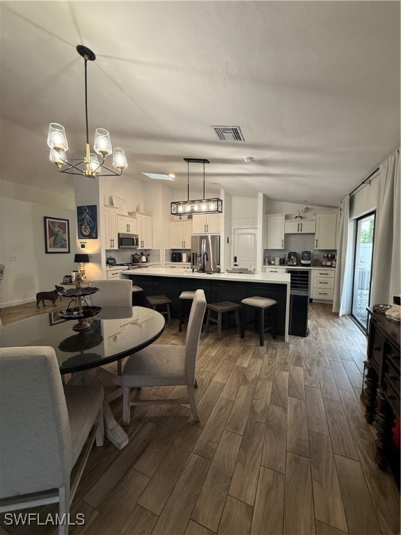 Dining area with wood tiled floors, a chandelier, and vaulted ceiling