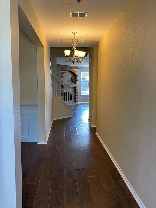 Hallway featuring an inviting chandelier and dark 