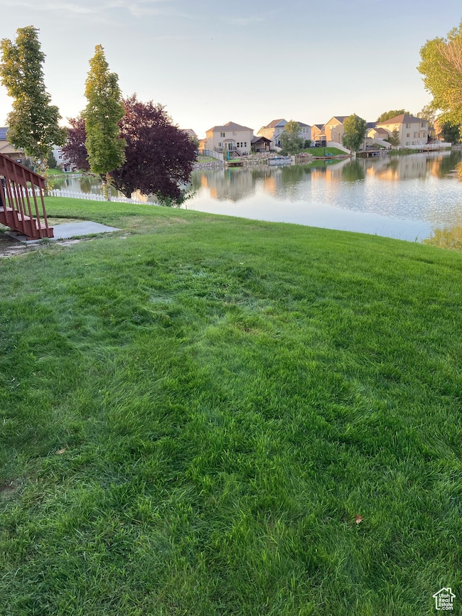 View of green lawn with a water view and a residential view