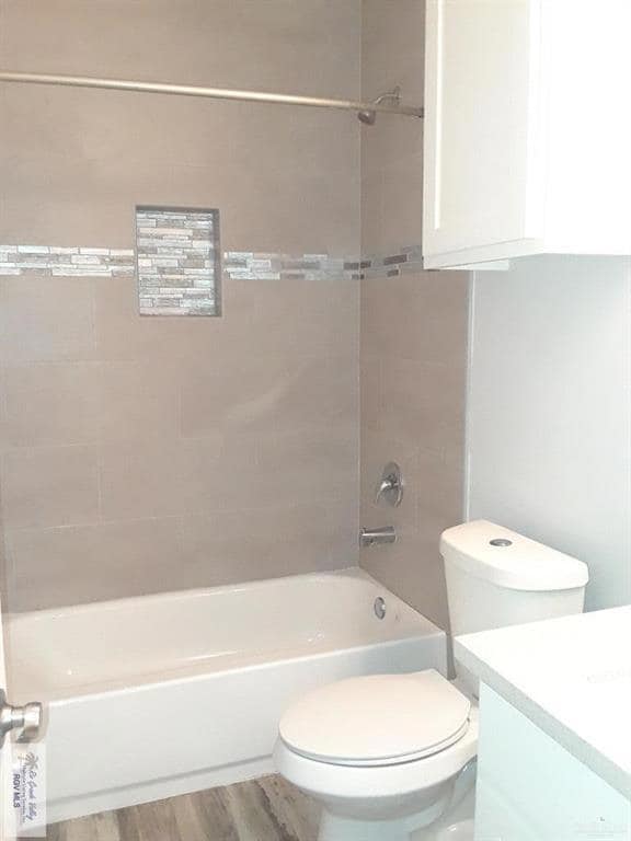 Bathroom featuring toilet, wood finished floors, bathtub / shower combination, and vanity