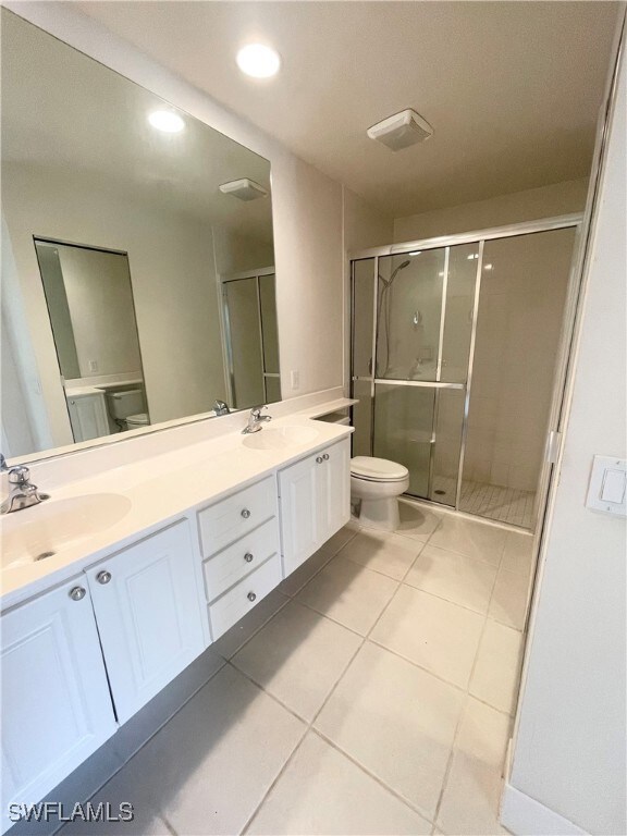 Bathroom with double vanity, a stall shower, tile