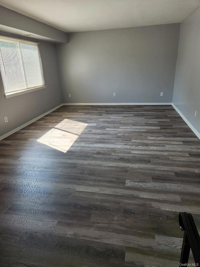 Unfurnished room featuring dark wood-type flooring and baseboards