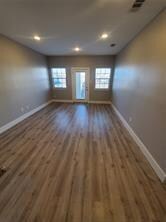 Unfurnished living room featuring visible vents, wood finished floors, and baseboards