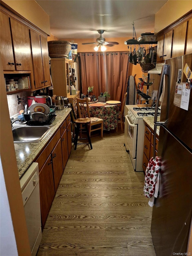 Kitchen featuring white appliances, light countertops, light wood-style flooring, a ceiling fan, and extractor fan