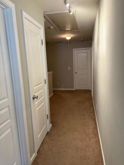 Hallway featuring attic access and light colored carpet